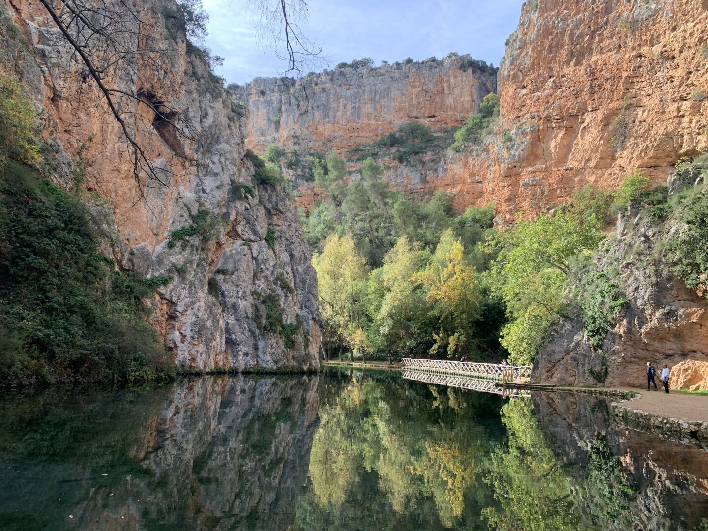 An autumn scene and mountains are reflected in a lake on a sunny day